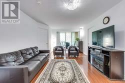 A living room with a grey couch and a rug in the middle.