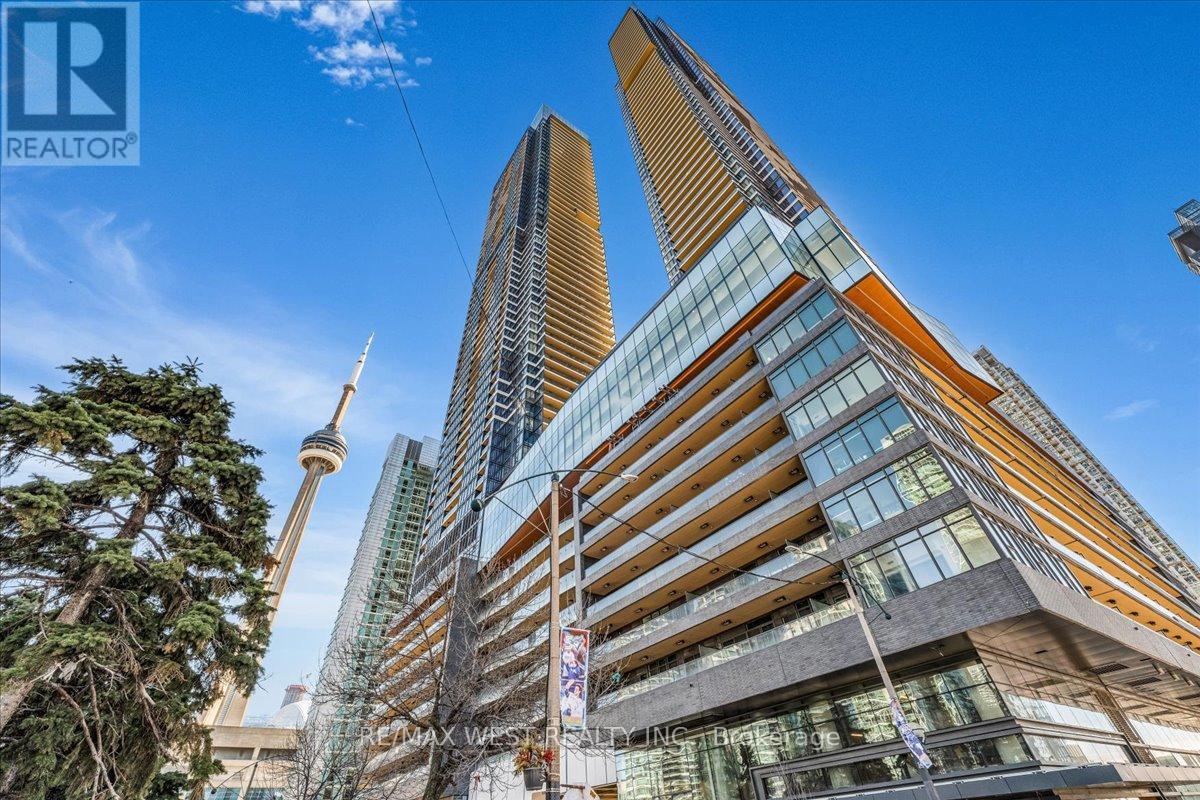 A tall building with a glass facade stands in front of a clear blue sky.