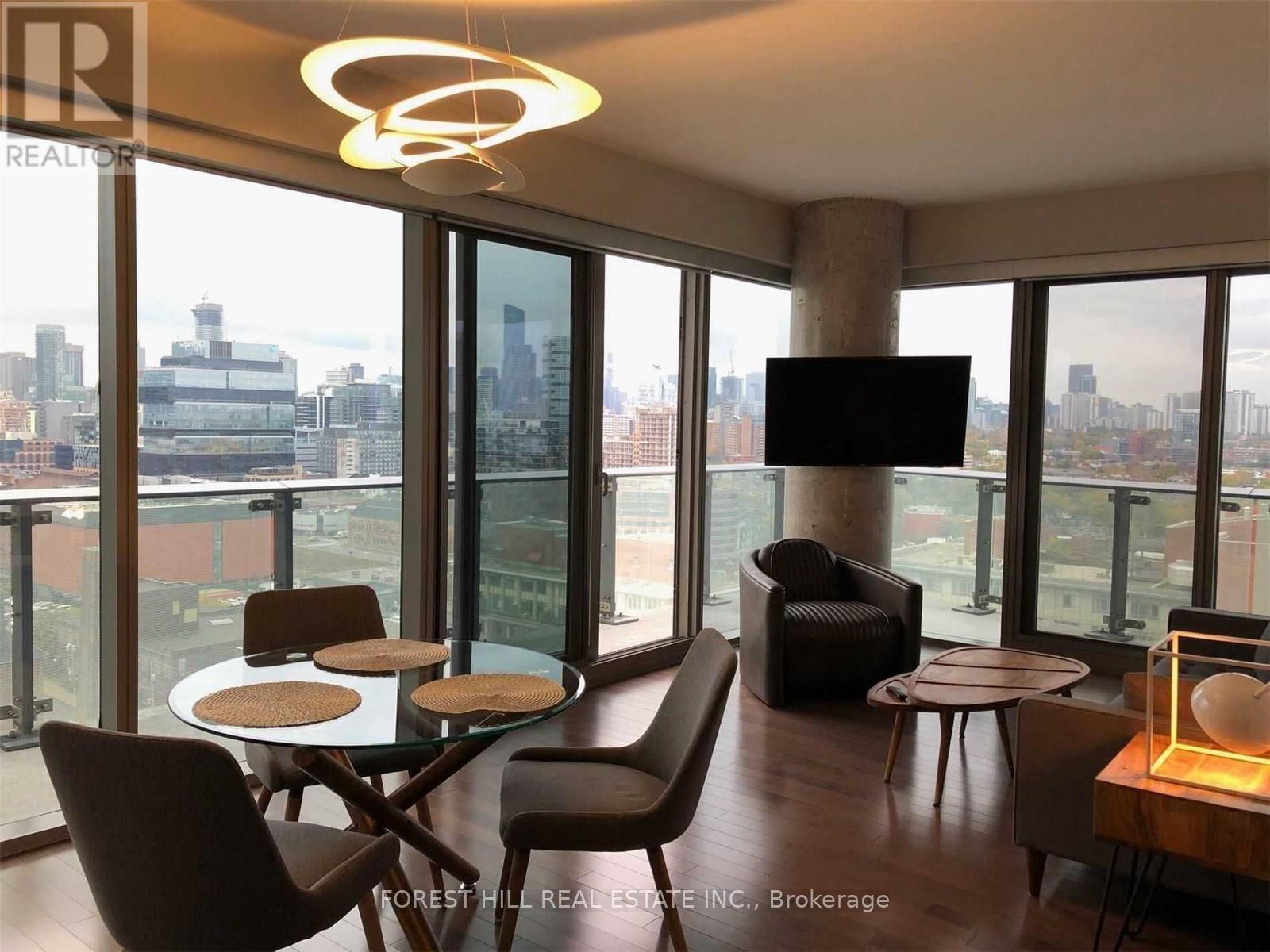 A living room with a glass table and chairs, a television, and a view of the city.