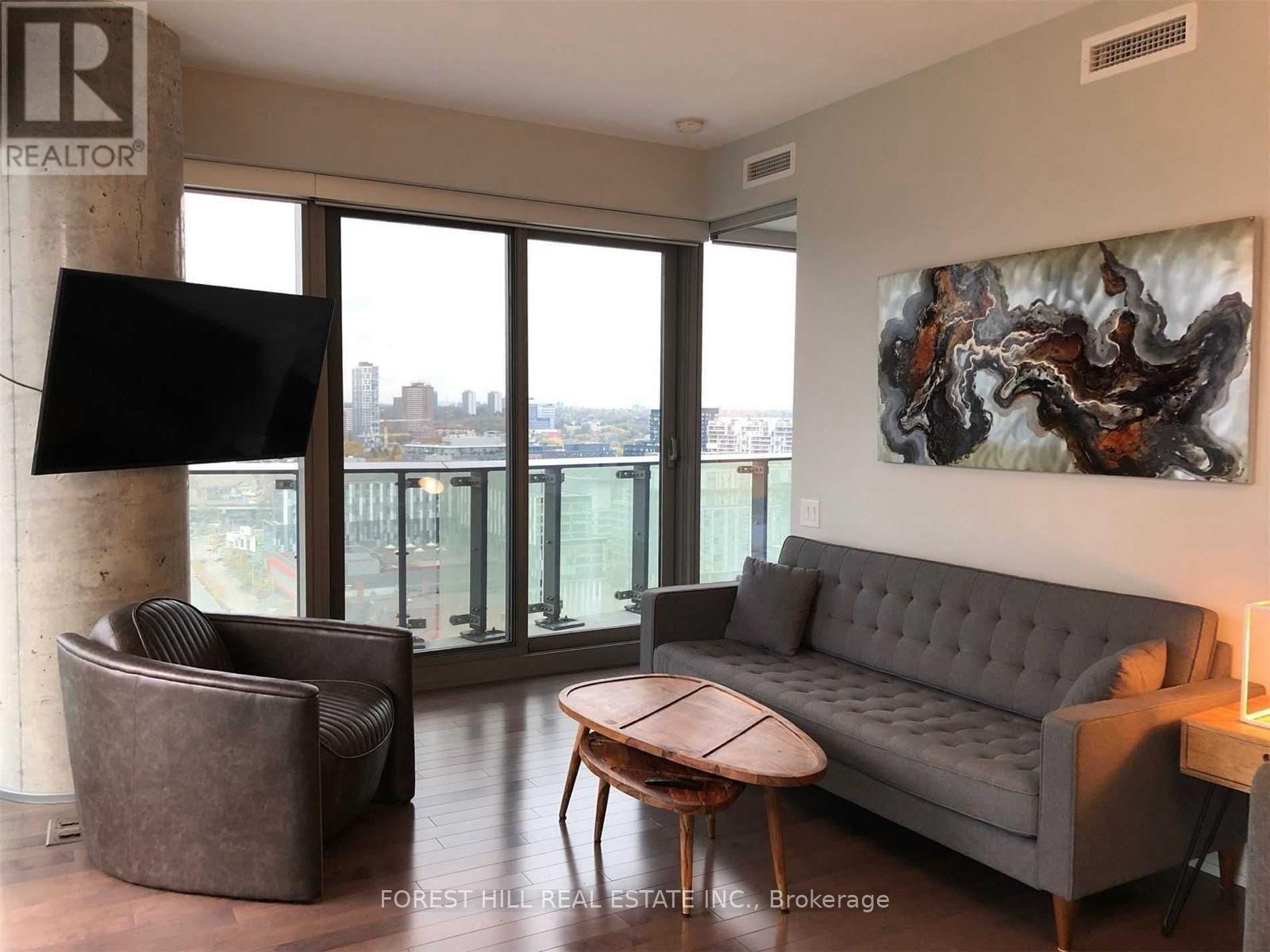 A living room with a grey couch, a brown chair, and a painting on the wall.