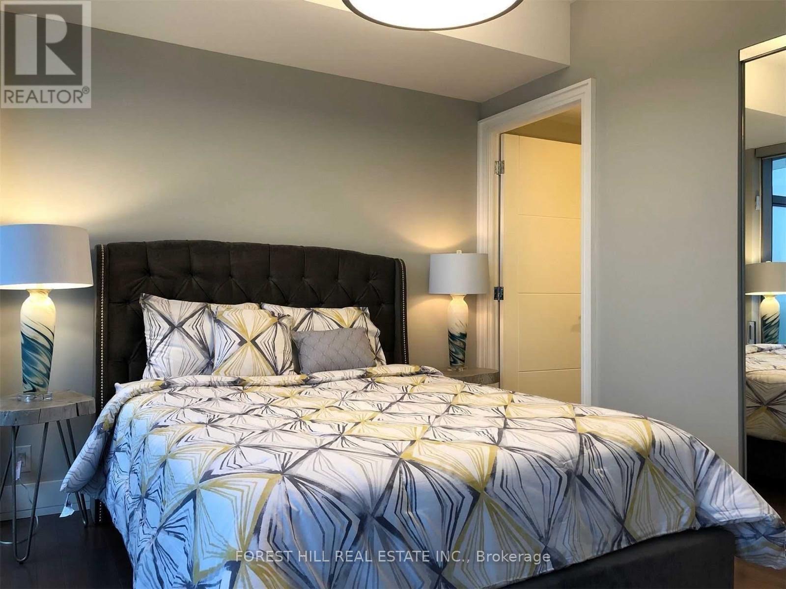 A bedroom with a large bed and a lamp on the side table.
