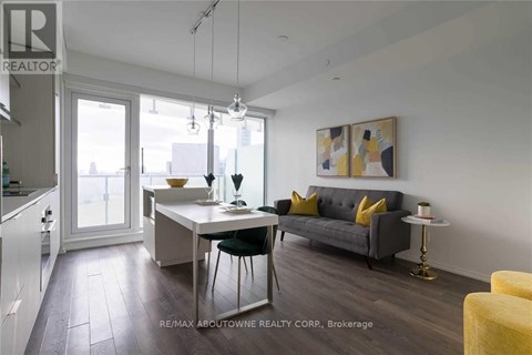 A modern living room with a grey couch and a dining table with chairs.