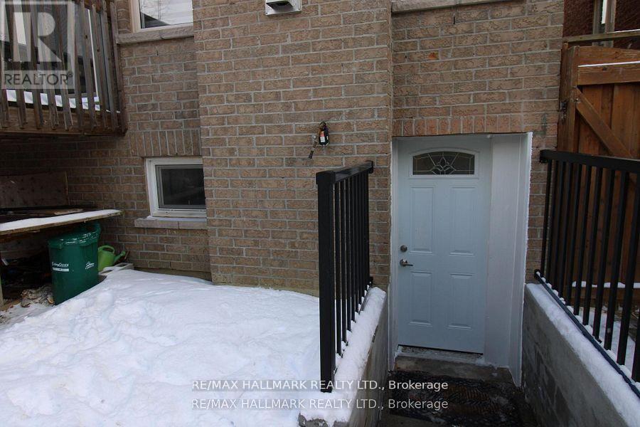 A small white door is on the side of a brick building.