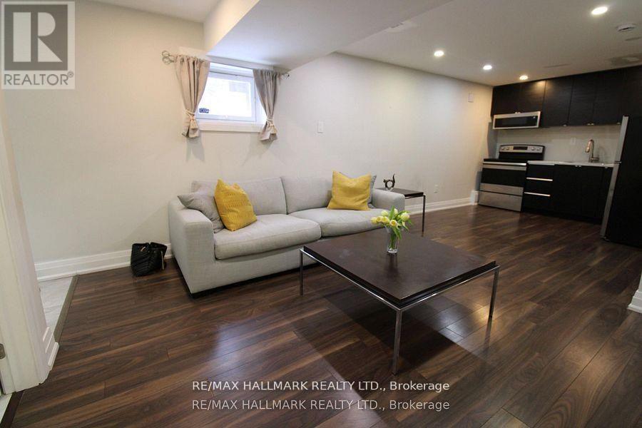 A living room with a grey couch, a coffee table, and a kitchen area in the background.