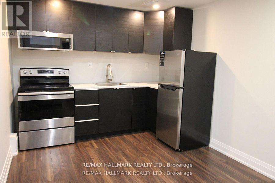 A modern kitchen with black cabinets and stainless steel appliances.