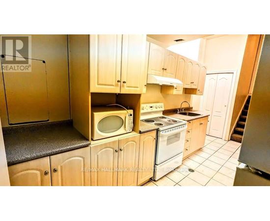 A kitchen with wooden cabinets and a microwave on top of the oven.