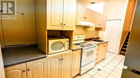 A kitchen with wooden cabinets and a microwave on top of the oven.