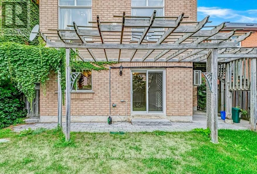 A patio with a pergola and a brick building in the background.