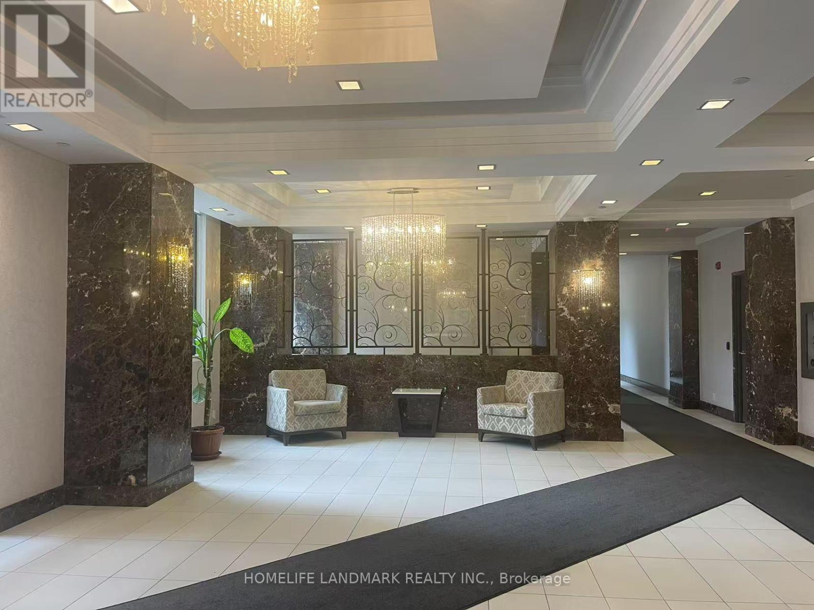 A lobby area with a marble wall and a chandelier.