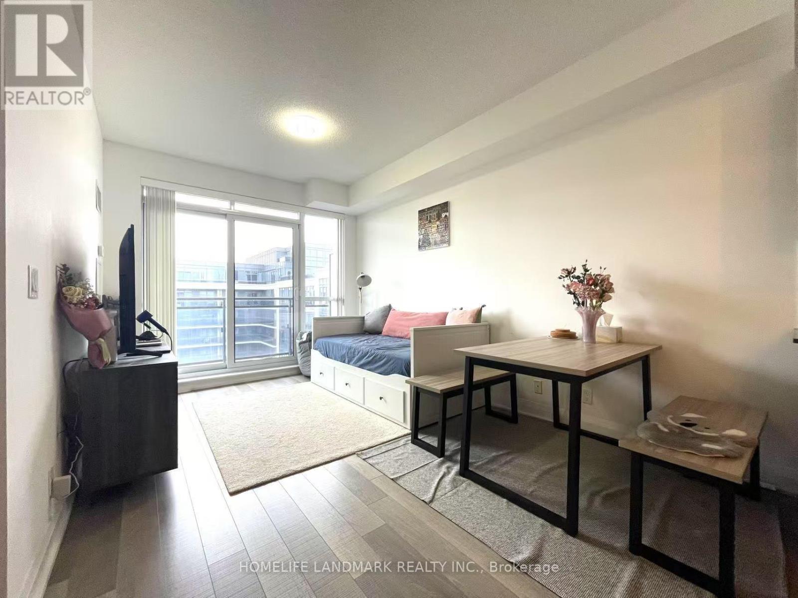 A bedroom with a bed, a table, and a window.