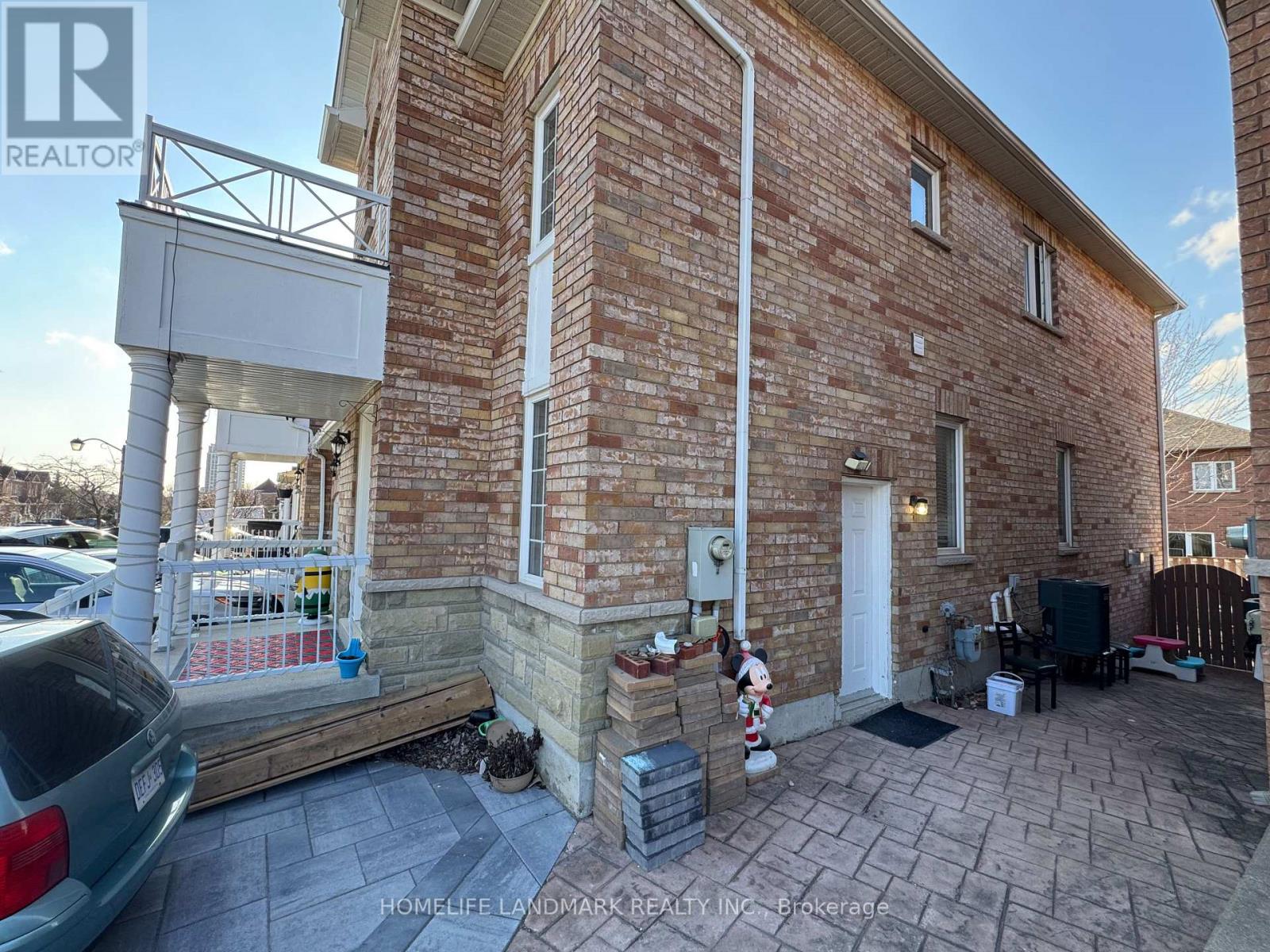 A brick house with a porch and a car parked in front.