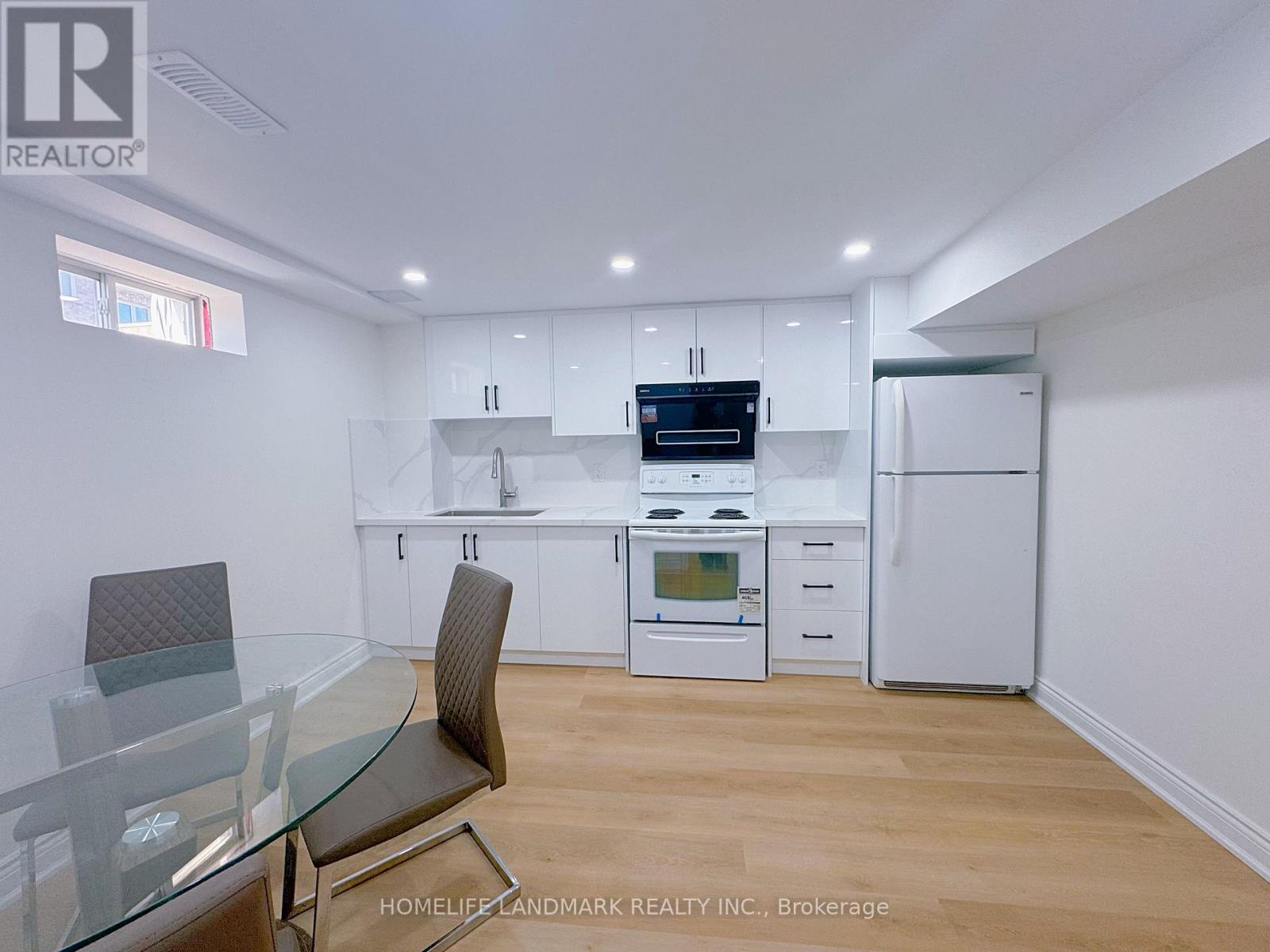 A modern kitchen with white cabinets and a glass table.