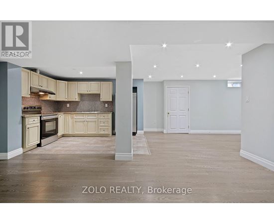 A spacious kitchen with beige cabinets and a tiled backsplash.