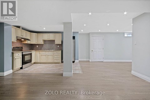 A spacious kitchen with beige cabinets and a tiled backsplash.