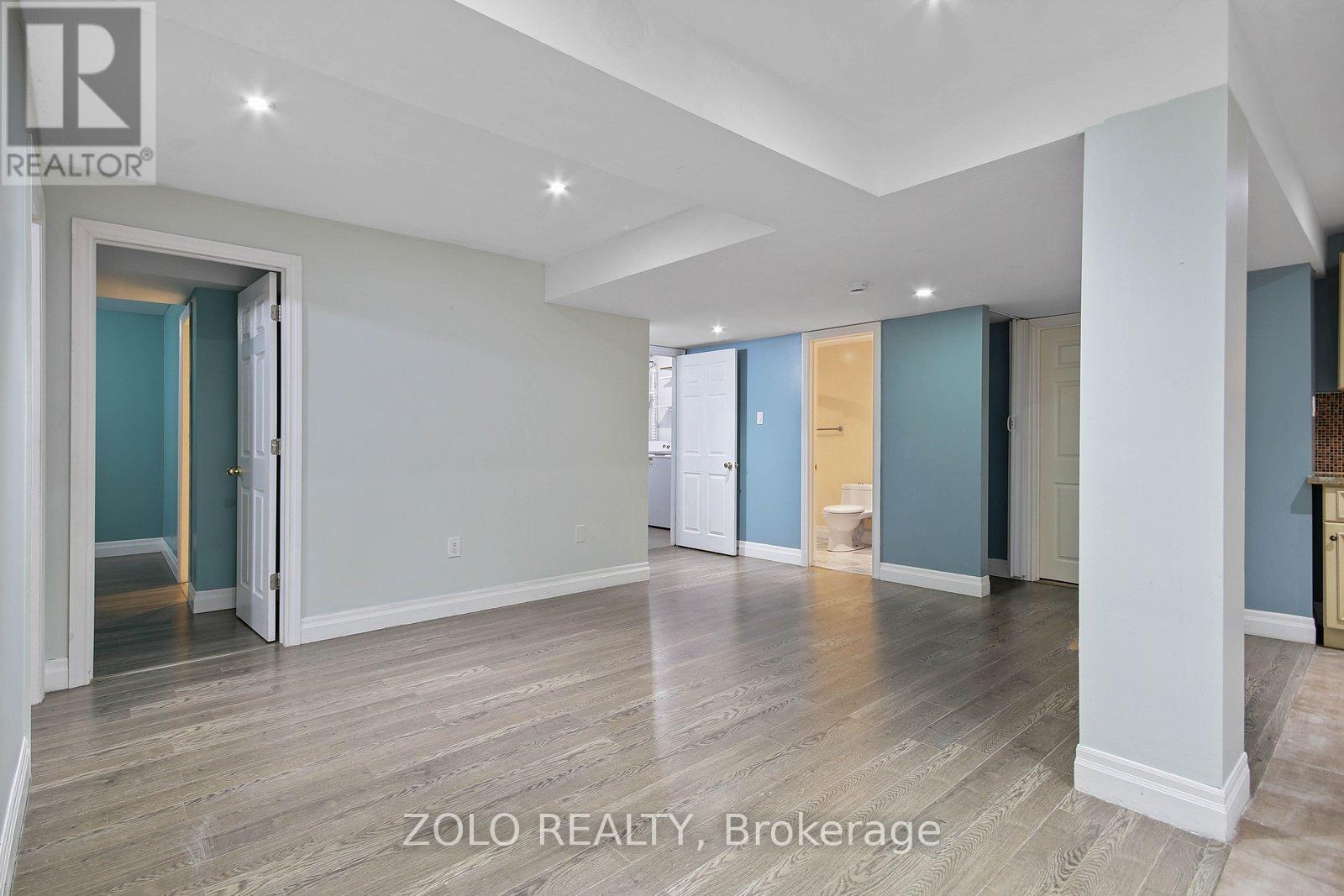 A spacious room with wooden flooring and white walls.