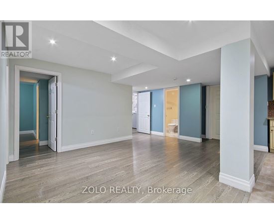 A spacious room with wooden flooring and white walls.