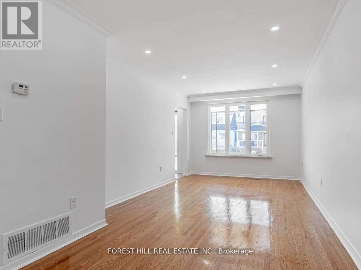 A spacious room with wooden flooring and white walls.