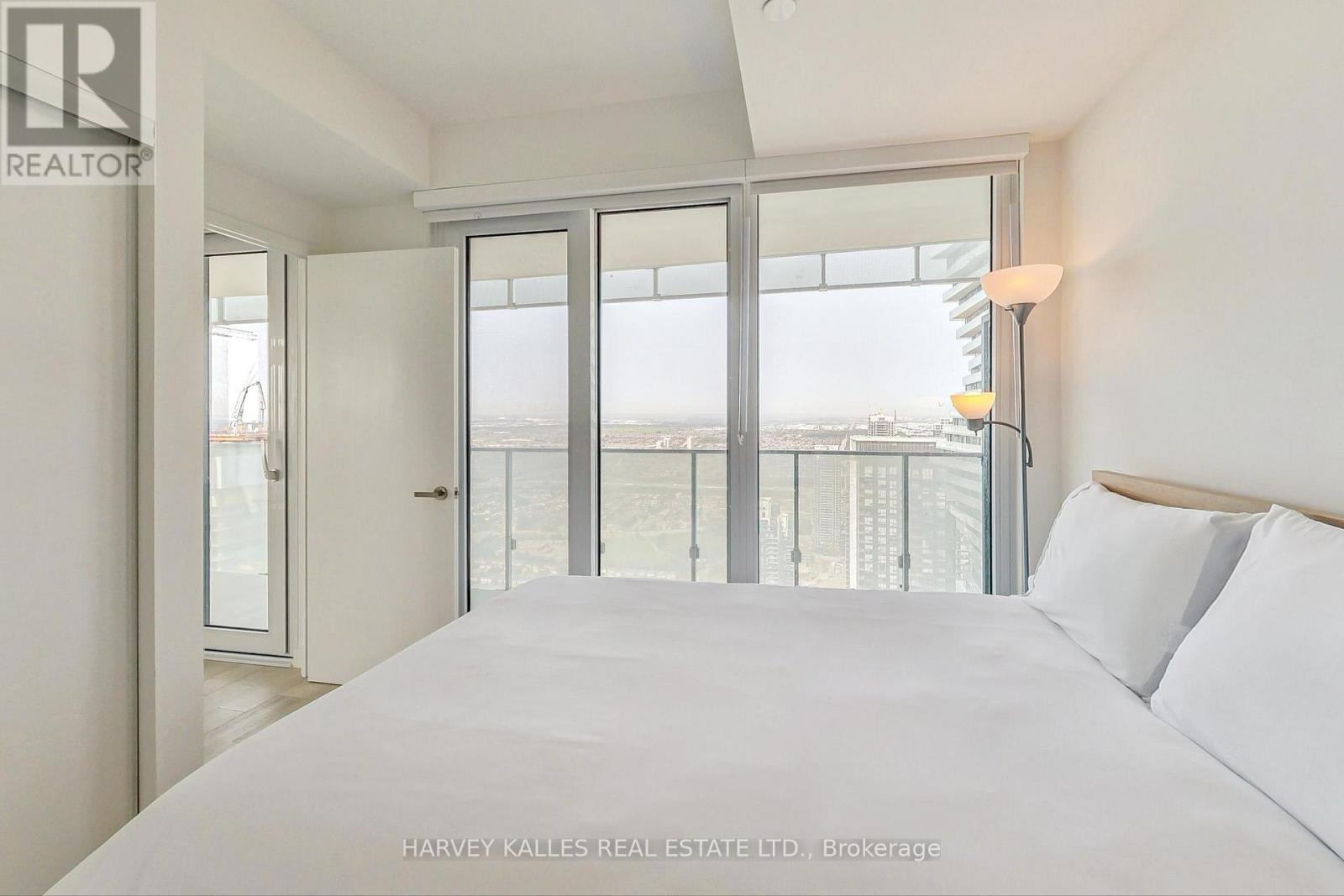 A bedroom with a large bed and a view of the city through the window.