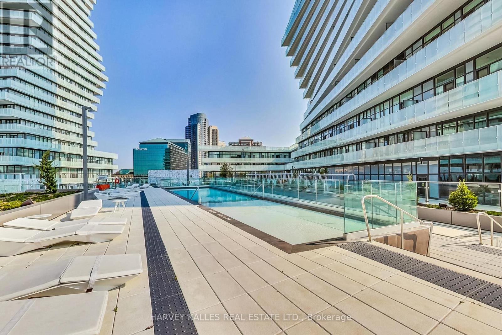 A rooftop pool area with sun loungers and a glass railing.