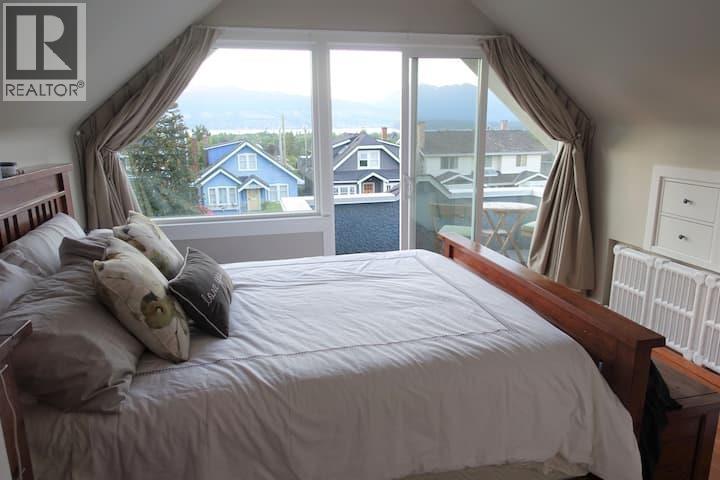 A bedroom with a large bed and a view of the outside through the window.