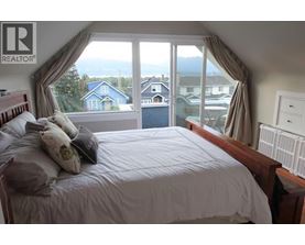 A bedroom with a large bed and a view of the outside through the window.