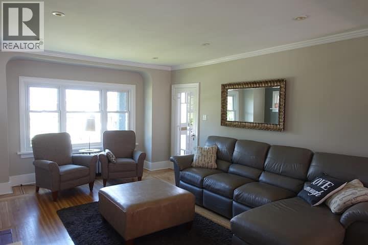 A living room with a black leather couch and a mirror on the wall.