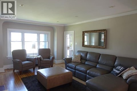 A living room with a black leather couch and a mirror on the wall.