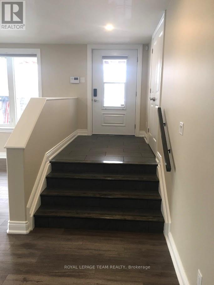 A hallway with a staircase leading to a door.
