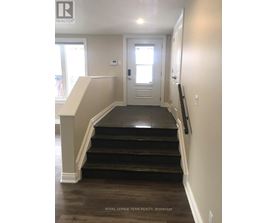A hallway with a staircase leading to a door.