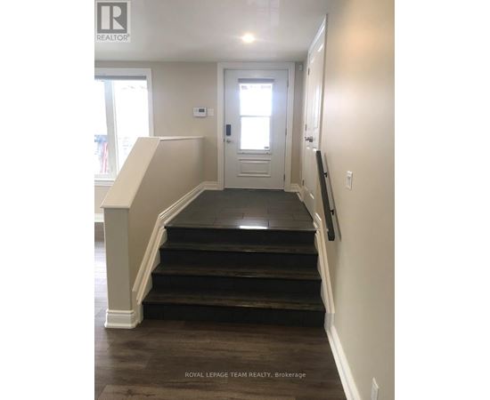 A hallway with a staircase leading to a door.