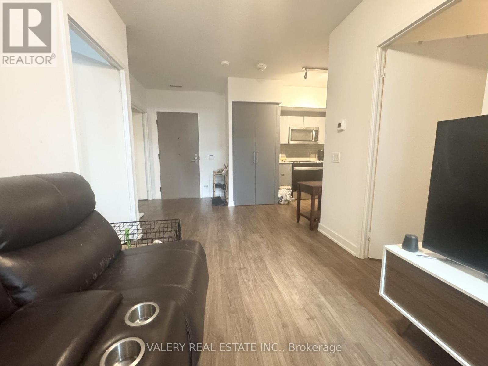 A living room with a black leather couch and a flat screen TV.