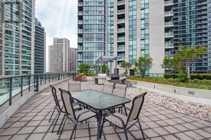 A table and chairs are set up on a patio with a view of a city skyline.