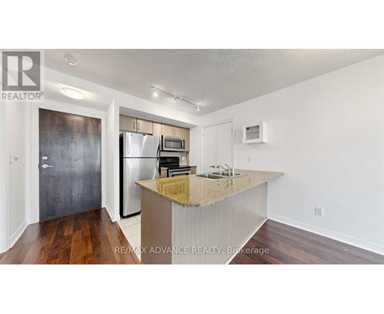 A kitchen with a granite countertop and a refrigerator with a stainless steel finish.