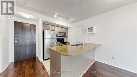 A kitchen with a granite countertop and a refrigerator with a stainless steel finish.