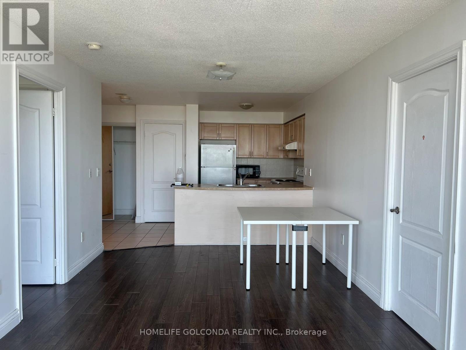 A white table is in the middle of a kitchen with wood floors.
