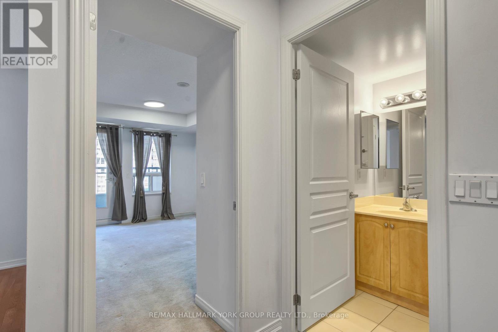 A bathroom with a sink, mirror, and a door leading to a bedroom.