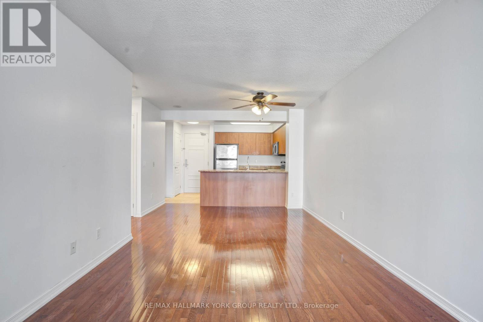 A spacious room with a wooden floor and a ceiling fan.