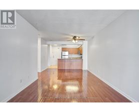 A spacious room with a wooden floor and a ceiling fan.