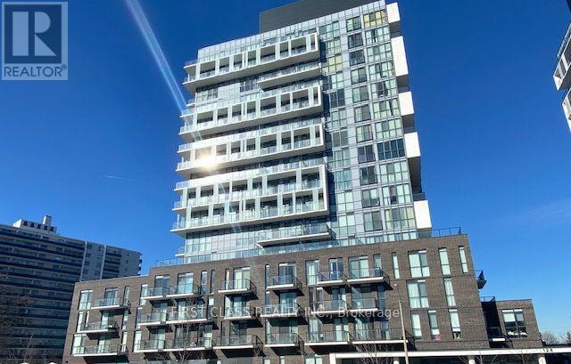 A tall building with a glass facade stands in front of a smaller building with a brick facade.