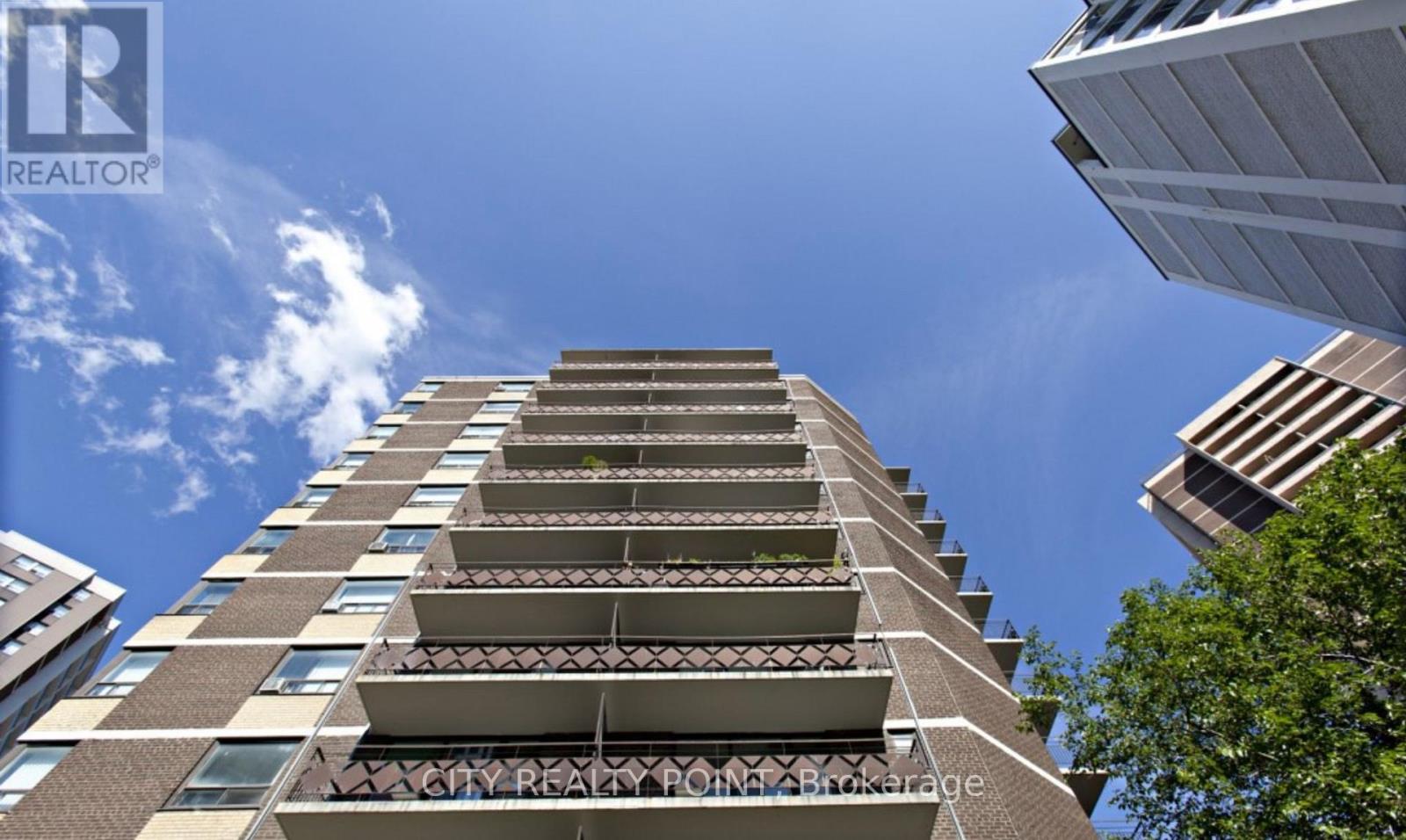 A tall residential building with balconies on the upper floors.