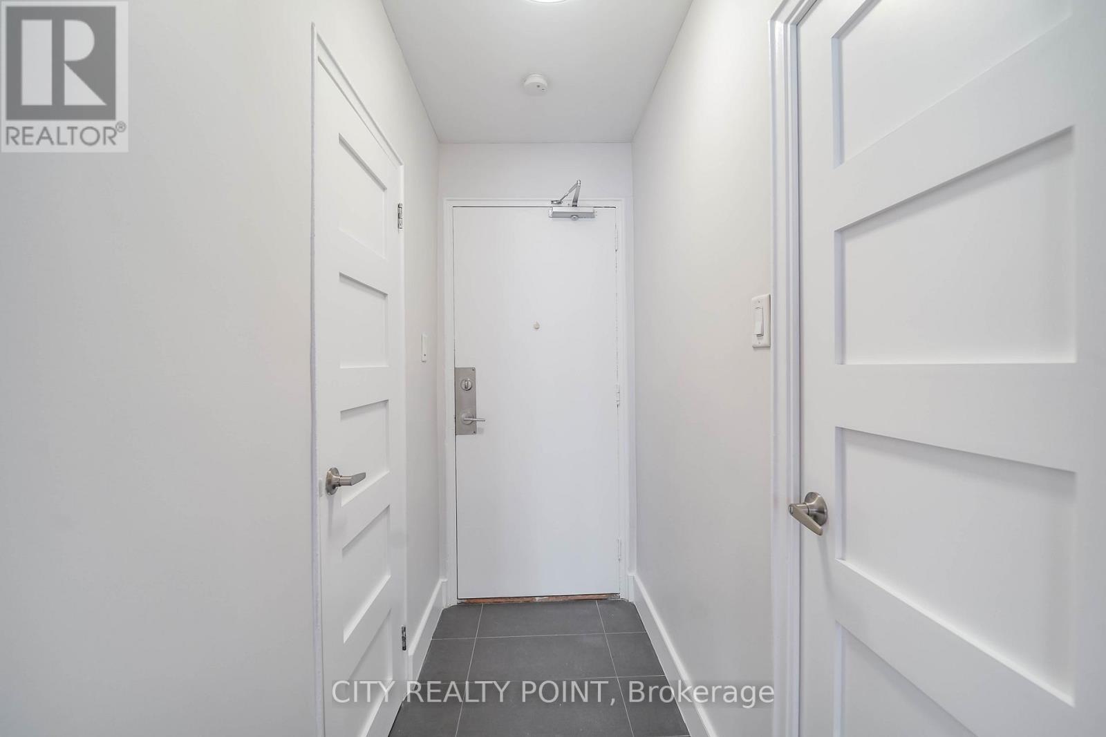 A hallway with white doors and a tiled floor.