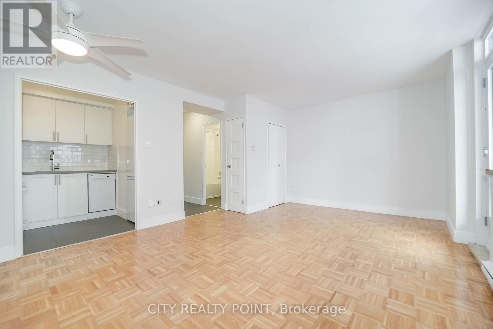 A spacious room with a wooden floor and white walls.