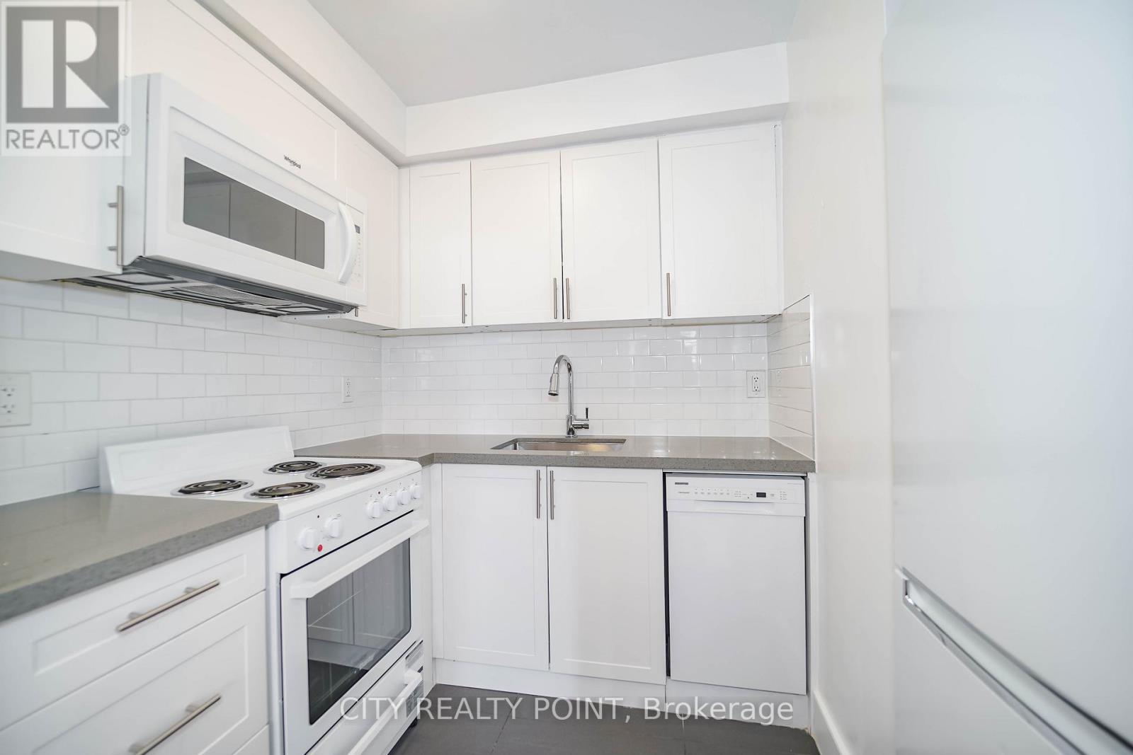 A kitchen with white cabinets and a stove top oven.