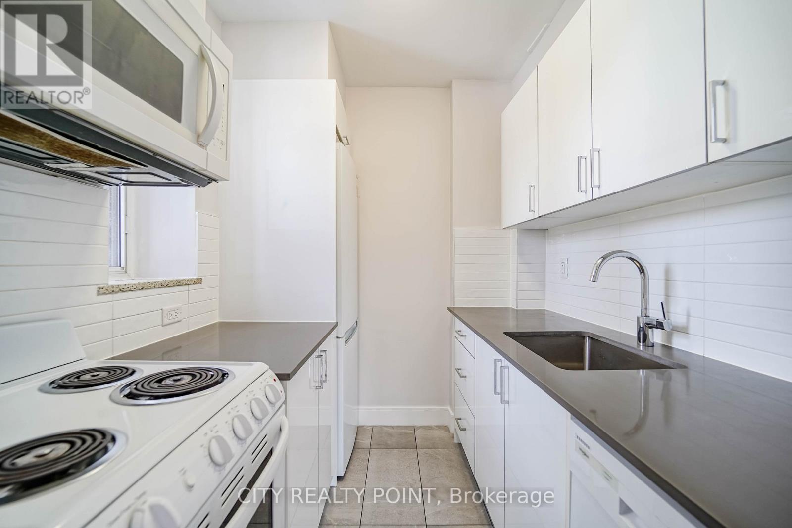 A kitchen with white cabinets and a stove top oven.