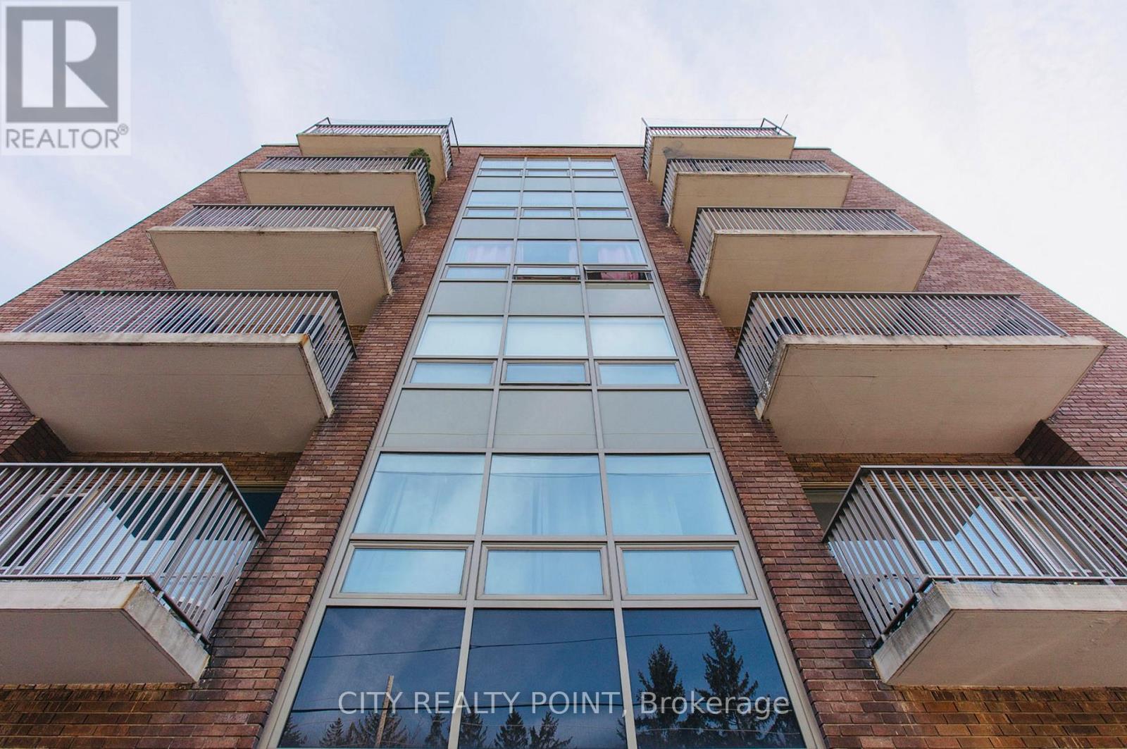 A tall building with balconies and a sign that reads "CITY REALTY POINT Brokerage".