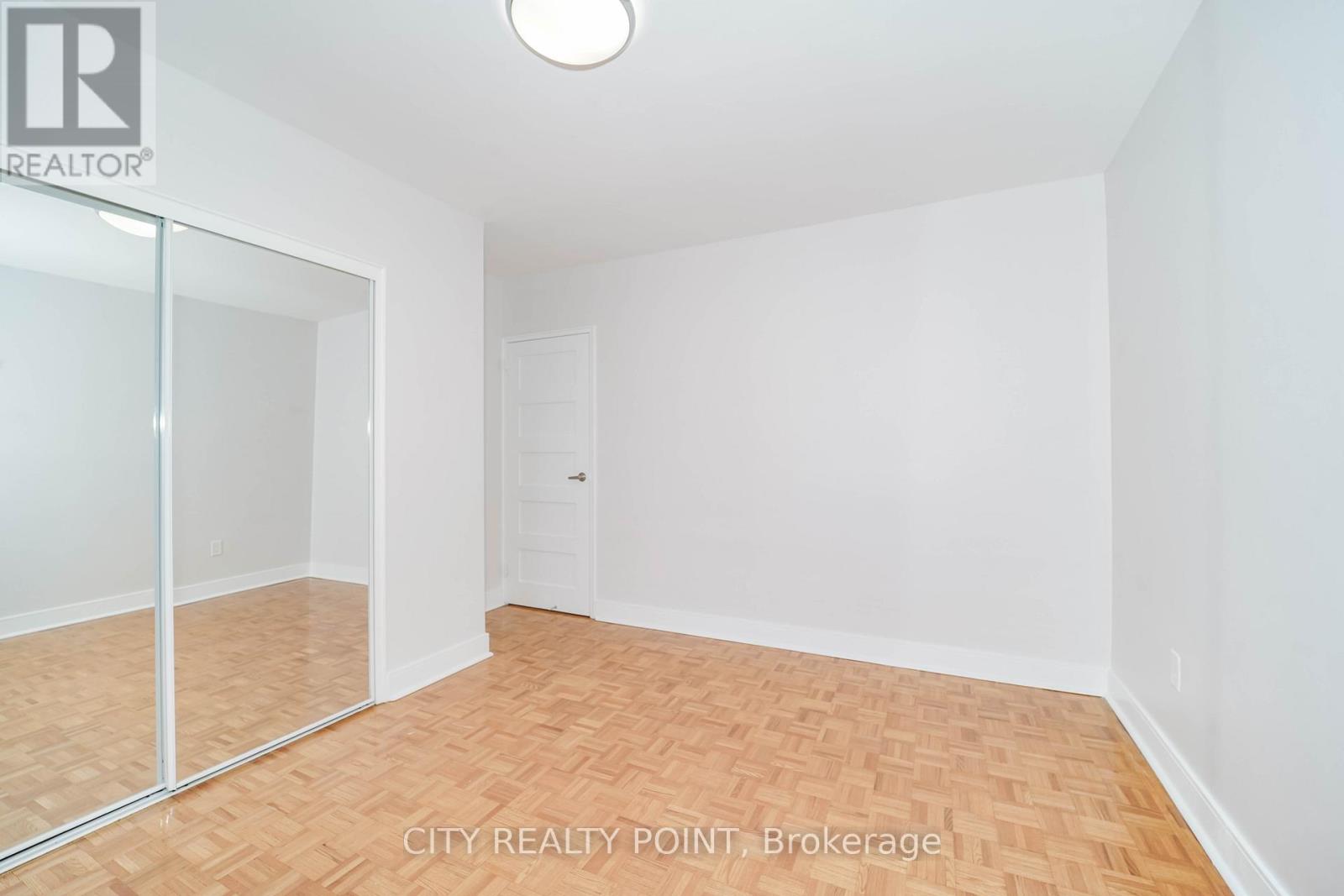 A room with a wooden floor and white walls, with a sliding glass door.