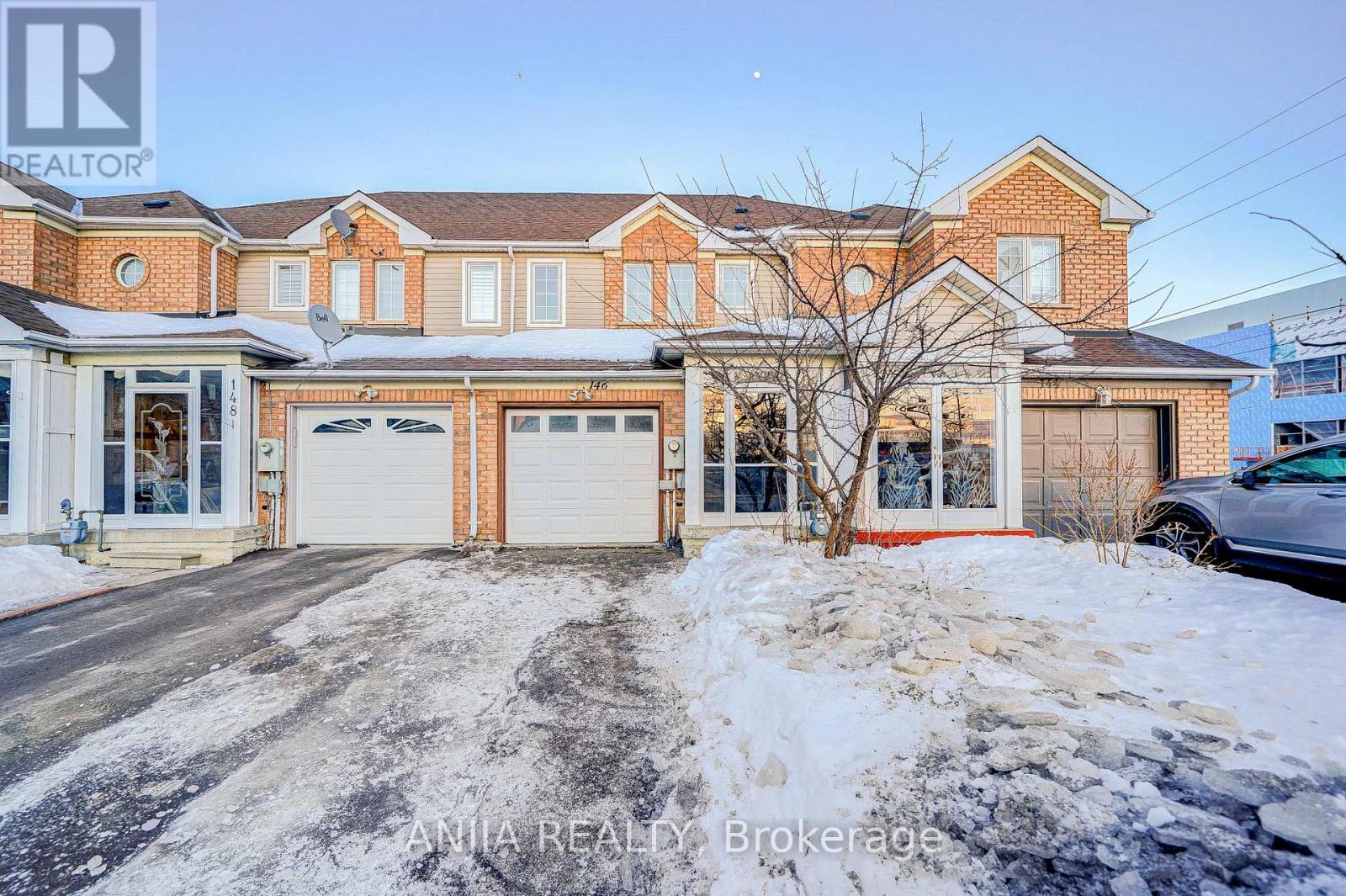A house with a red brick facade and a white garage door is for sale.