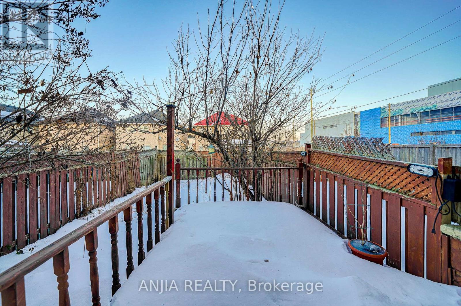 A snow-covered deck with a view of a red building in the distance.