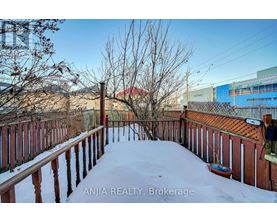 A snow-covered deck with a view of a red building in the distance.