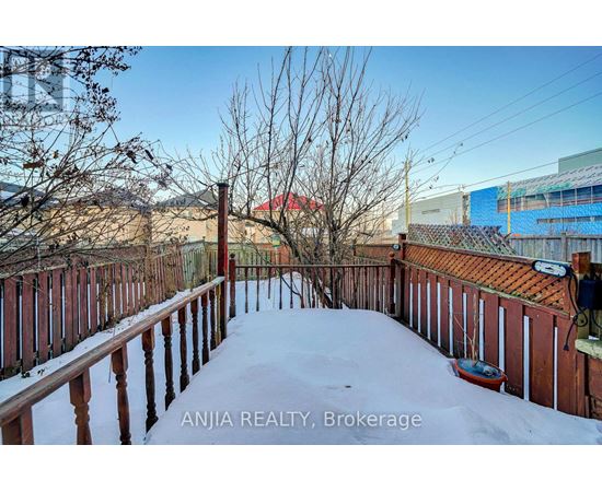 A snow-covered deck with a view of a red building in the distance.